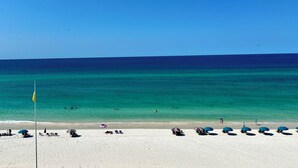Una playa con agua turquesa cristalina, arena blanca y varios sombrillas.