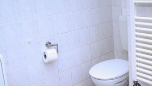 A bathroom with white tiles, a toilet, and a towel rack. - Comfortable single room with shared bathroom  (Plauen)