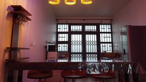 Angolo bar con sgabelli, una lampada a sospensione e una cucina sullo sfondo.