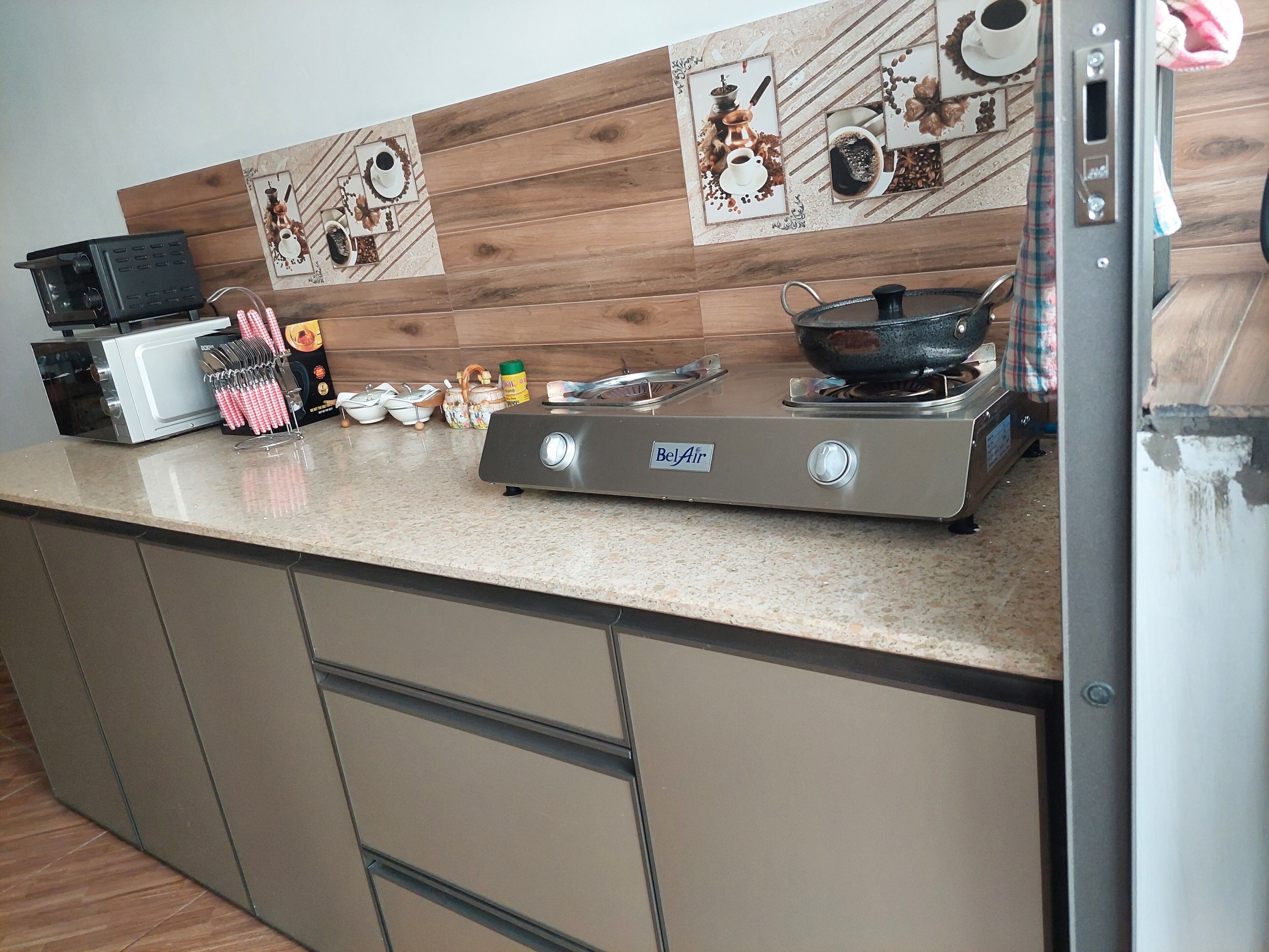 A kitchen with a microwave, stove, and various kitchen utensils.