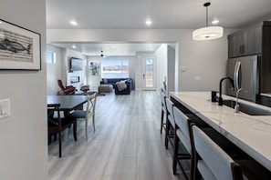 A modern kitchen with a large island, dark wooden chairs, and a dining area with a red chair. - Silver Creek Luxury Escape in Park City (Park City)