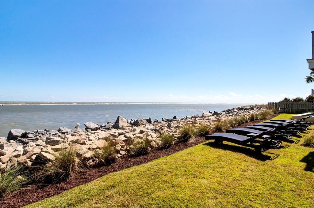 A beachside view with a row of sun loungers and a rocky shoreline.