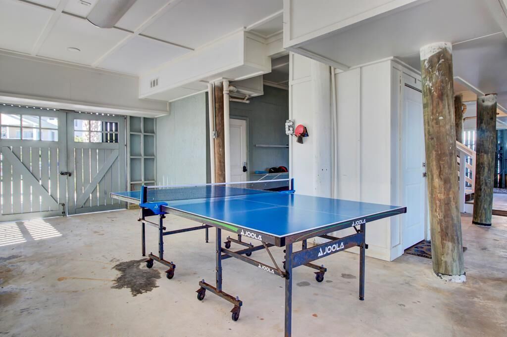 A ping pong table in a spacious room with a concrete floor, white walls, and a large window.