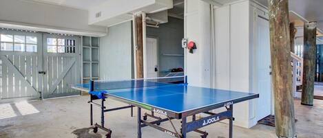 A ping pong table in a spacious room with a concrete floor, white walls, and a large window.