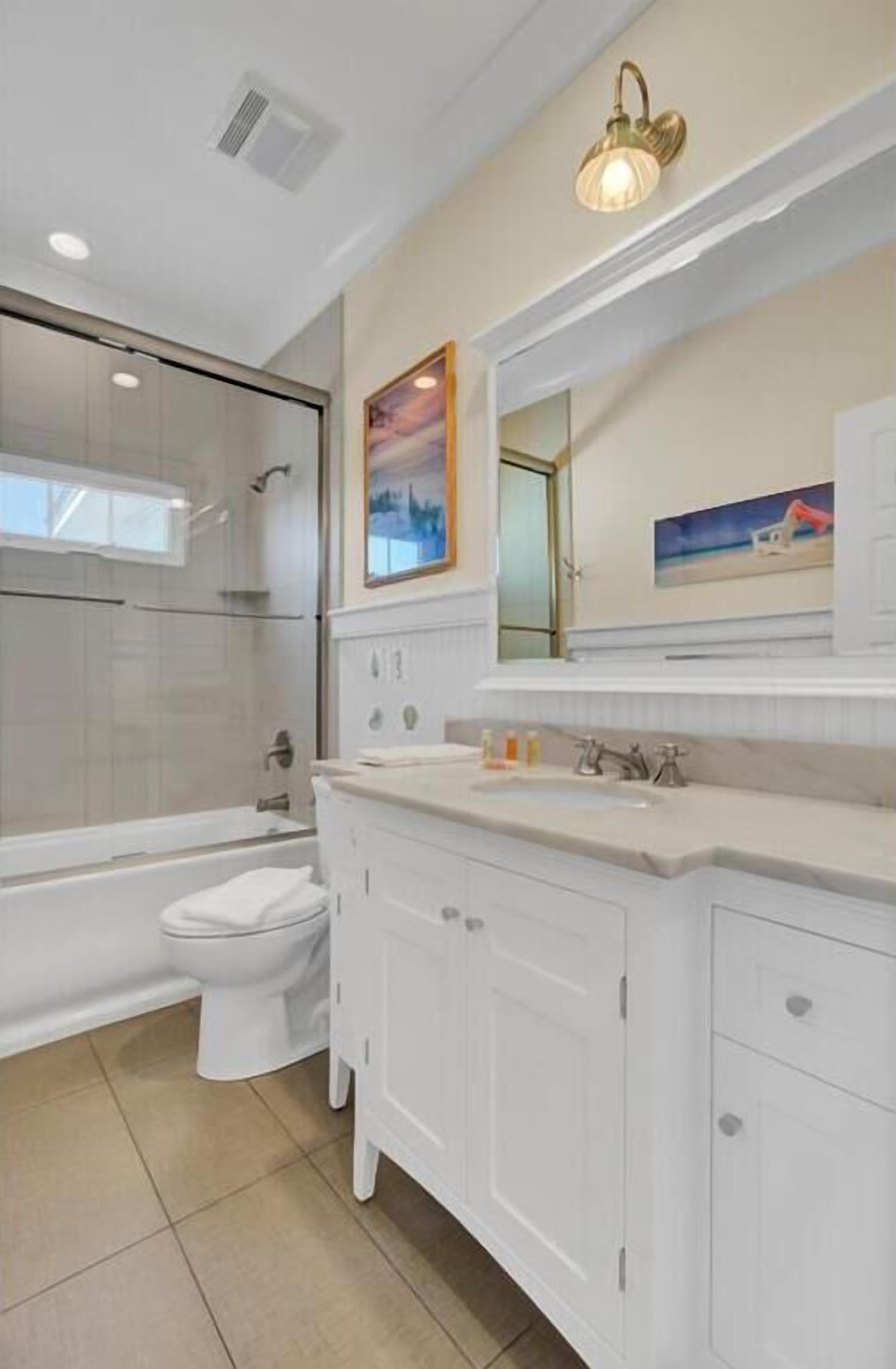 A modern bathroom with a glass shower enclosure, a white toilet, and a vanity with a mirror.