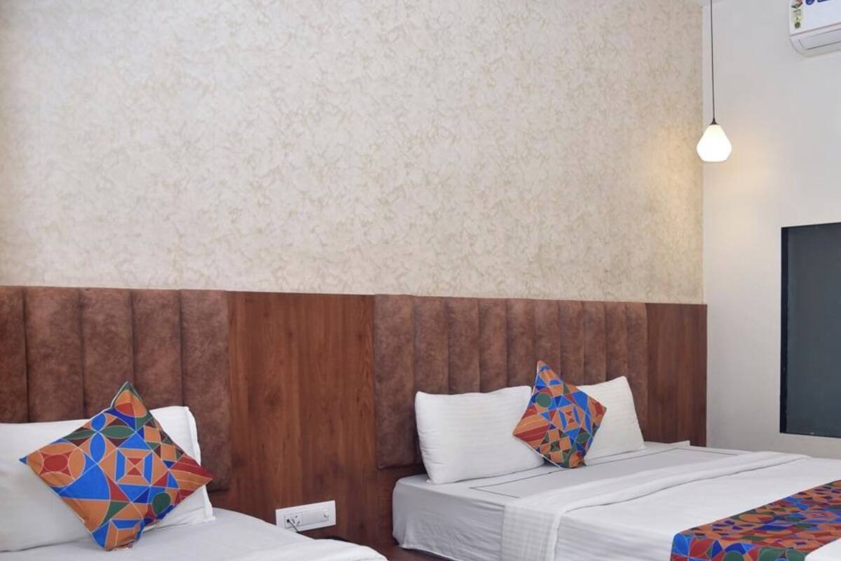 A hotel room with two beds, each with a geometric-patterned throw blanket and pillows.