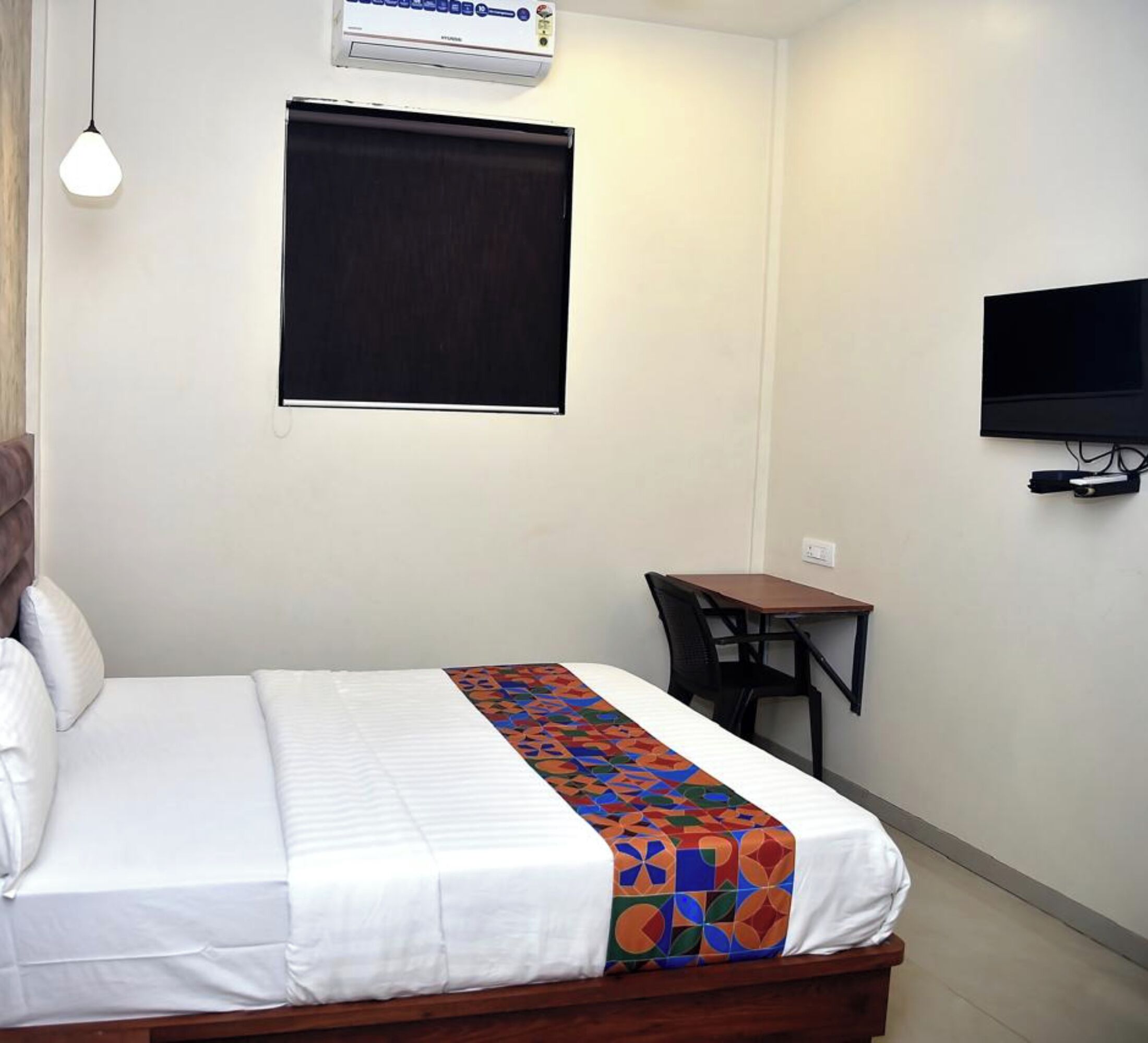 Une chambre d’hôtel équipée d’un lit, d’un bureau, d’une chaise, d’une télévision et d’un appareil de climatisation.