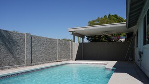 A swimming pool with clear blue water, surrounded by a stone wall and a covered patio area. - Charming 2-bedroom house in marvelous Phoenix with pool🌴 (Phoenix)