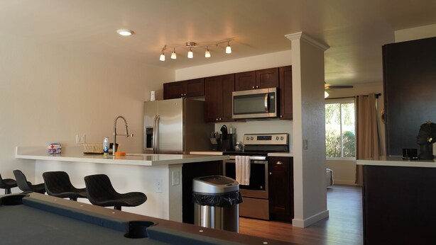A modern kitchen with dark wooden cabinets, stainless steel appliances, and a central island with seating. - Charming 2-bedroom house in marvelous Phoenix with pool🌴 (Phoenix)