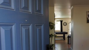 A hallway with a blue door, a wooden floor, a dining table, a potted plant, and a trash can. - Charming 2-bedroom house in marvelous Phoenix with pool🌴 (Phoenix)
