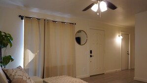 A living room with a white sofa, a fluffy throw blanket, a ceiling fan, and a door with a light above it. - Charming 2-bedroom house in marvelous Phoenix with pool🌴 (Phoenix)