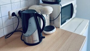 Une cuisine équipée d’une machine à café, d’un grille-pain et d’un four à micro-ondes, le tout posé sur un plan de travail.