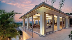 Een modern huis met een glazen woonkamer, een balkon en uitzicht op het landschap.