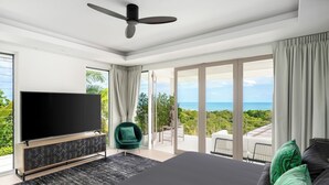A modern bedroom with a large bed, a flat-screen TV, a ceiling fan, and a view of the ocean. - Villa Kohia, 5 BR, sea views, North Chaweng (Surat Thani)