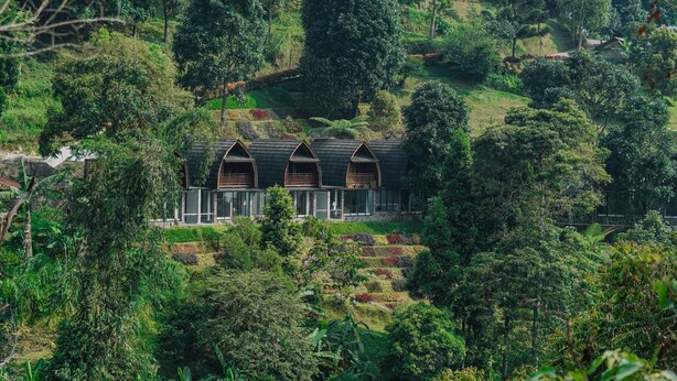 A hillside hotel with multiple rooms featuring dark roofs and wooden balconies. - Damar Langit Resort (Cisarua)