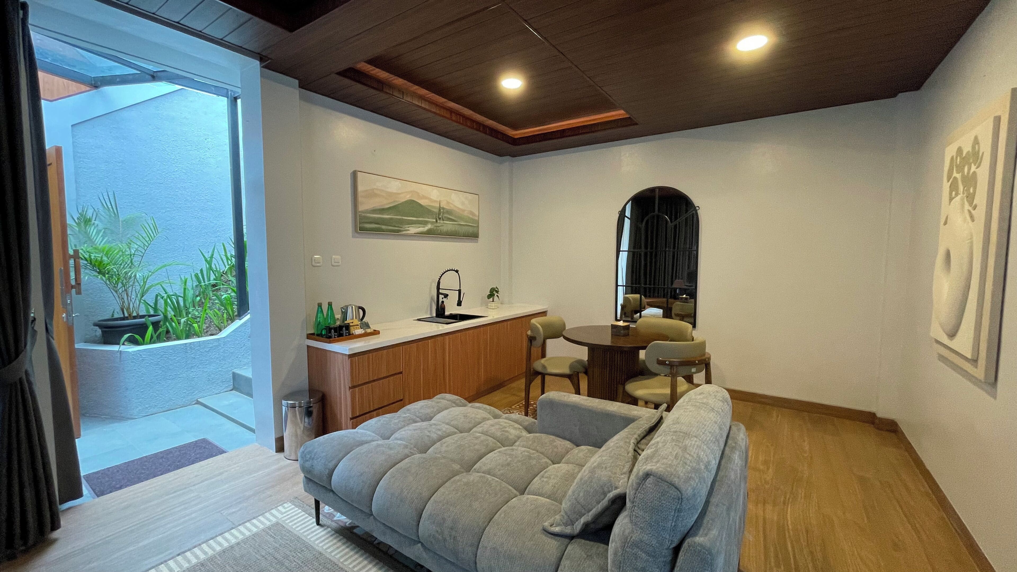 A compact living space with a kitchenette, a sofa, a dining area, and a view through a glass door.