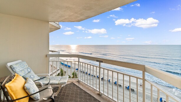 A balcony with a view of the ocean, a 'No Smoking' sign, and beach umbrellas. - Garden City Beach Oceanfront Condo 508 | Rising Tides Properties Rental (Murrells Inlet)