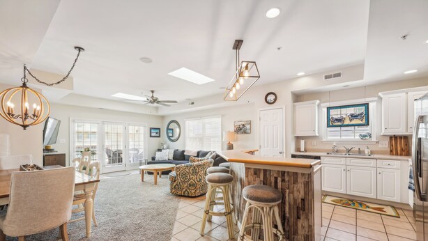 A spacious living area with a dining table, bar stools, and a kitchen with white cabinets.