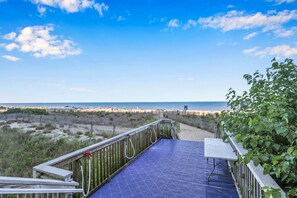 Ein Holzdeck mit einer blauen Sicherheitsmatte, das zum Blick auf den Strand führt.