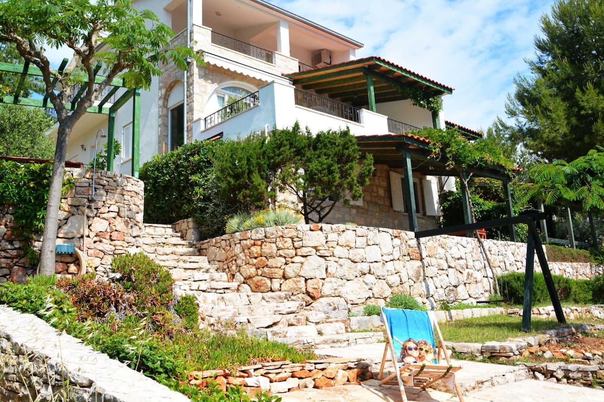 A two-story building with a stone wall, a covered outdoor seating area, and a balcony.