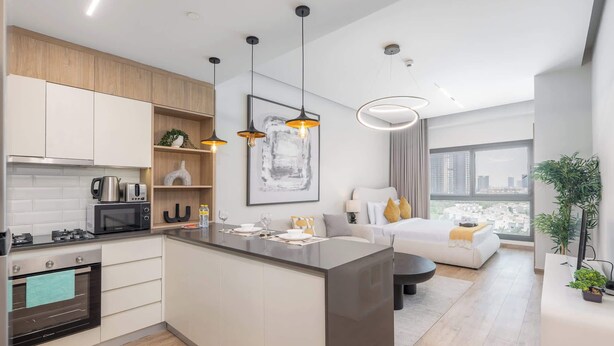 A modern kitchen with a central island, built-in appliances, and pendant lighting. - StayShort - Elegant Studio in Rokane G25 Good for 2 (Dubai)