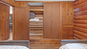 A bedroom with a wooden wardrobe, a bed, and a small desk.