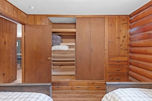 A bedroom with a wooden wardrobe, a bed, and a small desk. - Sapphire Ridge Cabin (Hamilton)