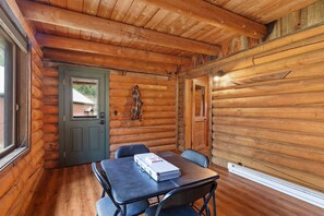 A log cabin interior with a dining table and chairs, a door with a window, and a coat rack. - Sapphire Ridge Cabin (Hamilton)