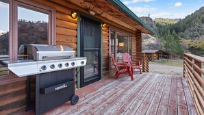 A wooden cabin with a grill and outdoor seating.