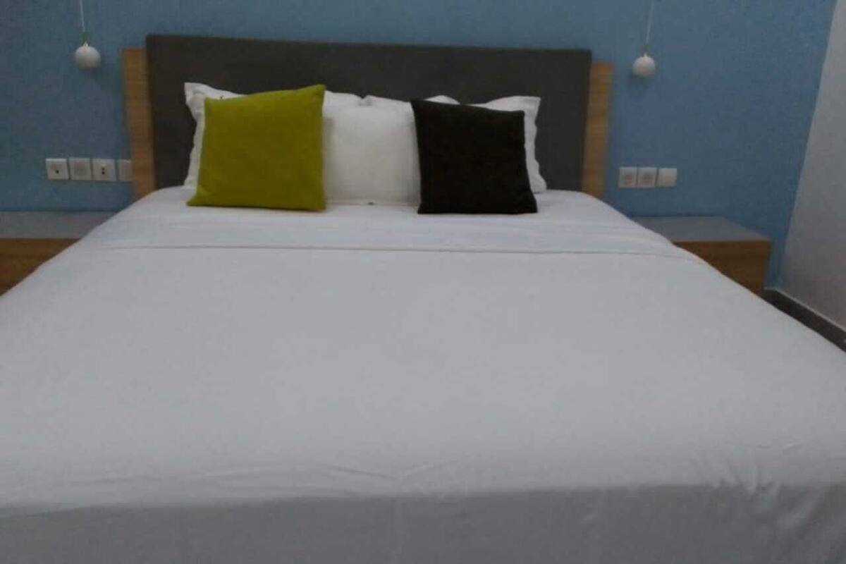 Ein Bett mit weißer Bettdecke und drei Kissen in verschiedenen Farben.