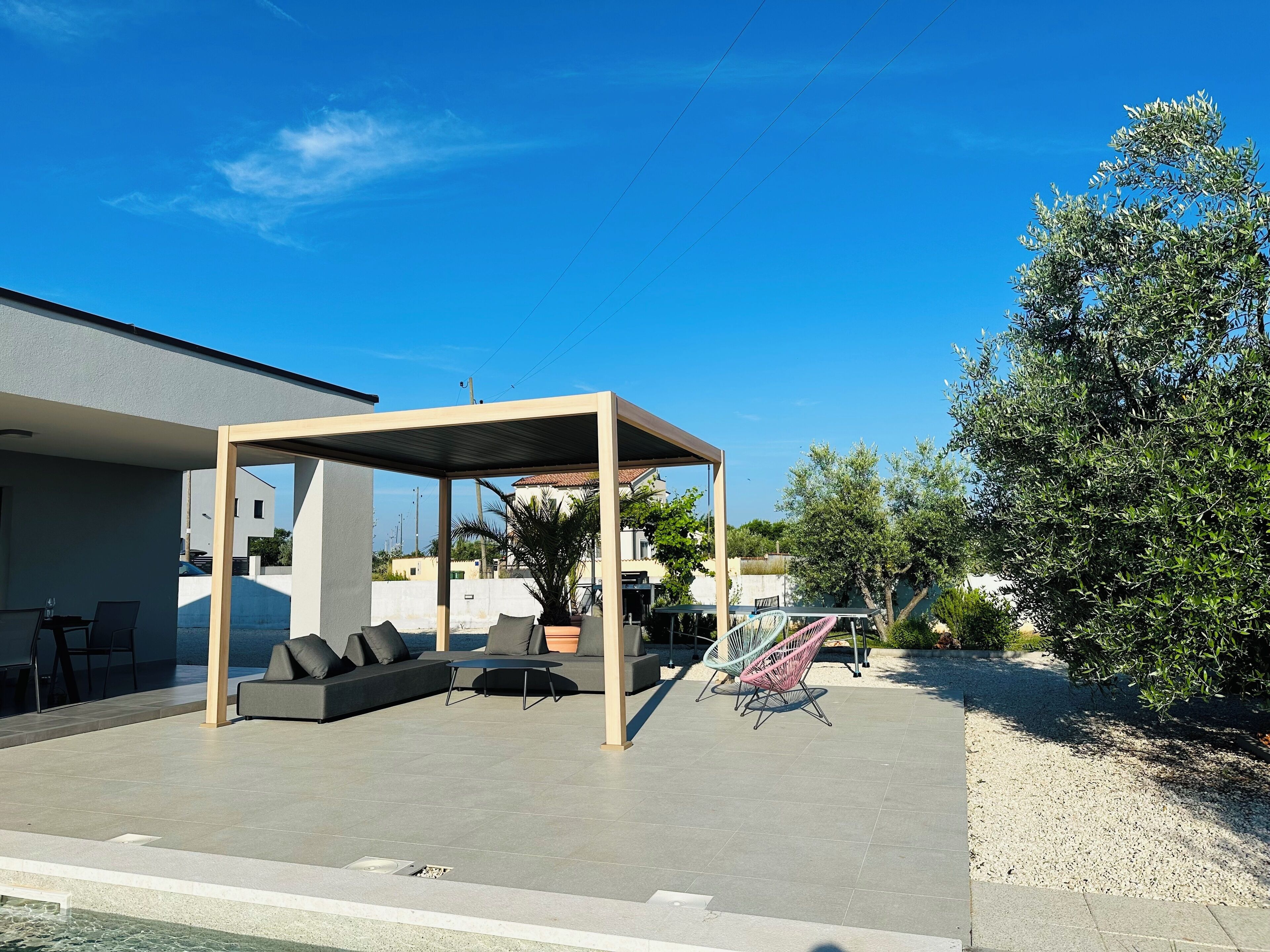 An outdoor patio with a covered seating area, a hammock, and a pool.