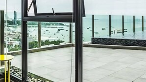 A modern balcony with a glass railing overlooking a marina and cityscape. - The BASE Central Pattaya By INH Global (Pattaya)