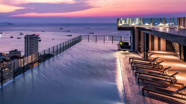 A rooftop pool with a view of the sea and cityscape at sunset. - The BASE Central Pattaya By INH Global (Pattaya)