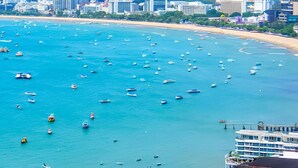 A coastal cityscape with a beach, numerous boats, and high-rise buildings. - The BASE Central Pattaya By INH Global (Pattaya)