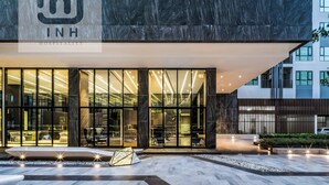 A modern hotel entrance with large glass doors, a marble facade, and a well-lit outdoor seating area. - The BASE Central Pattaya By INH Global (Pattaya)