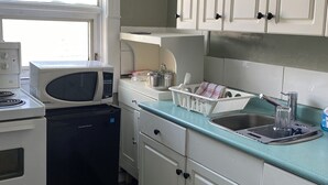 Ett kompakt kök med vita skåp, en mikrovågsugn, en spis och en diskmaskin.