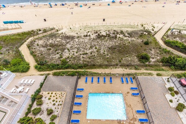 Vista aérea de una playa con piscina y tumbonas.