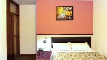 A hotel room with a bed, a nightstand, a telephone, and a painting on the wall.