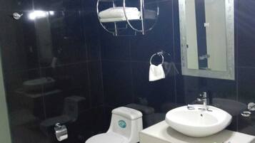 A modern bathroom with a white toilet, a white sink, and a towel rack.