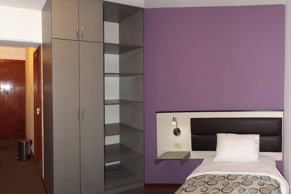 A hotel room with a bed, a wardrobe, and a mirror.