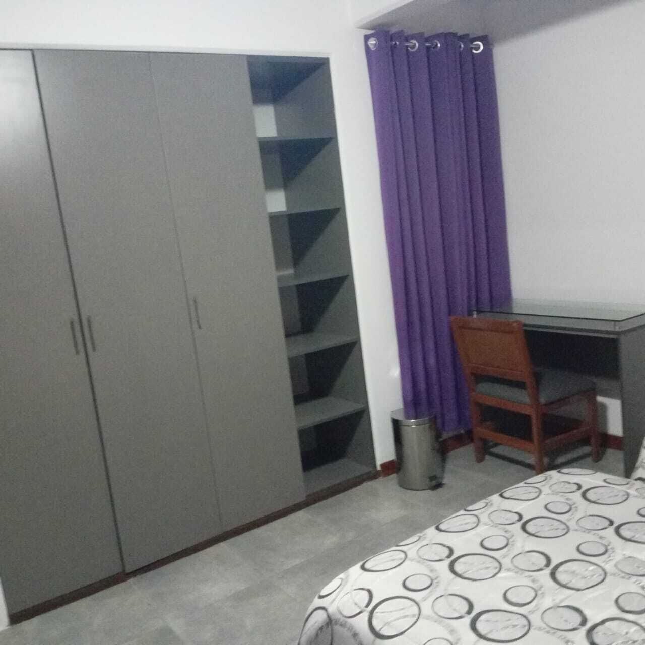 A bedroom with a bed, a desk, a chair, and a wardrobe.