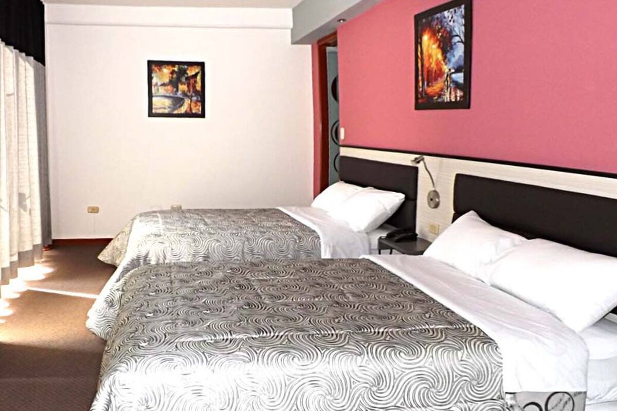 A hotel room with two beds, a staircase, and artwork on the walls.