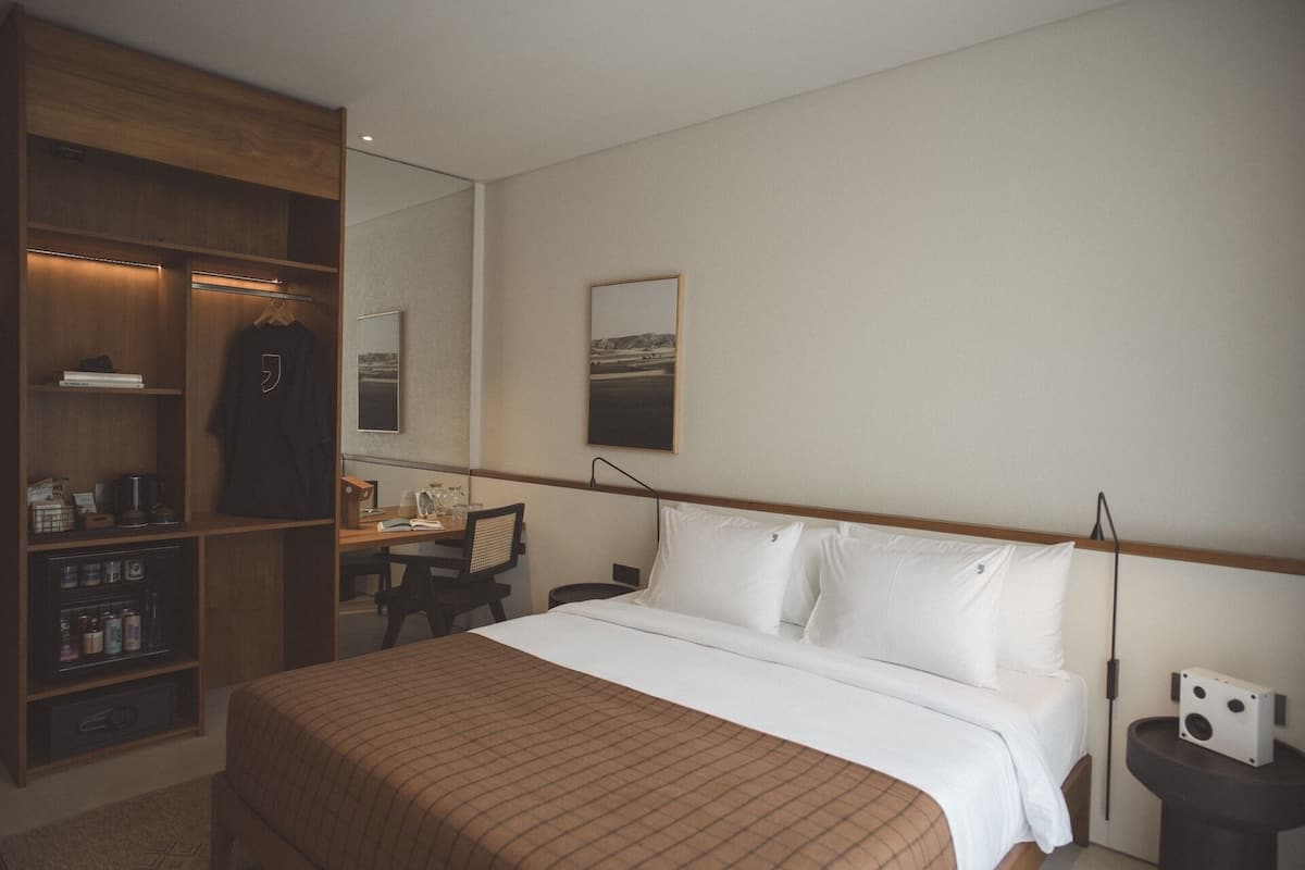 A hotel room with a bed, a desk, a wardrobe, and a mirror.