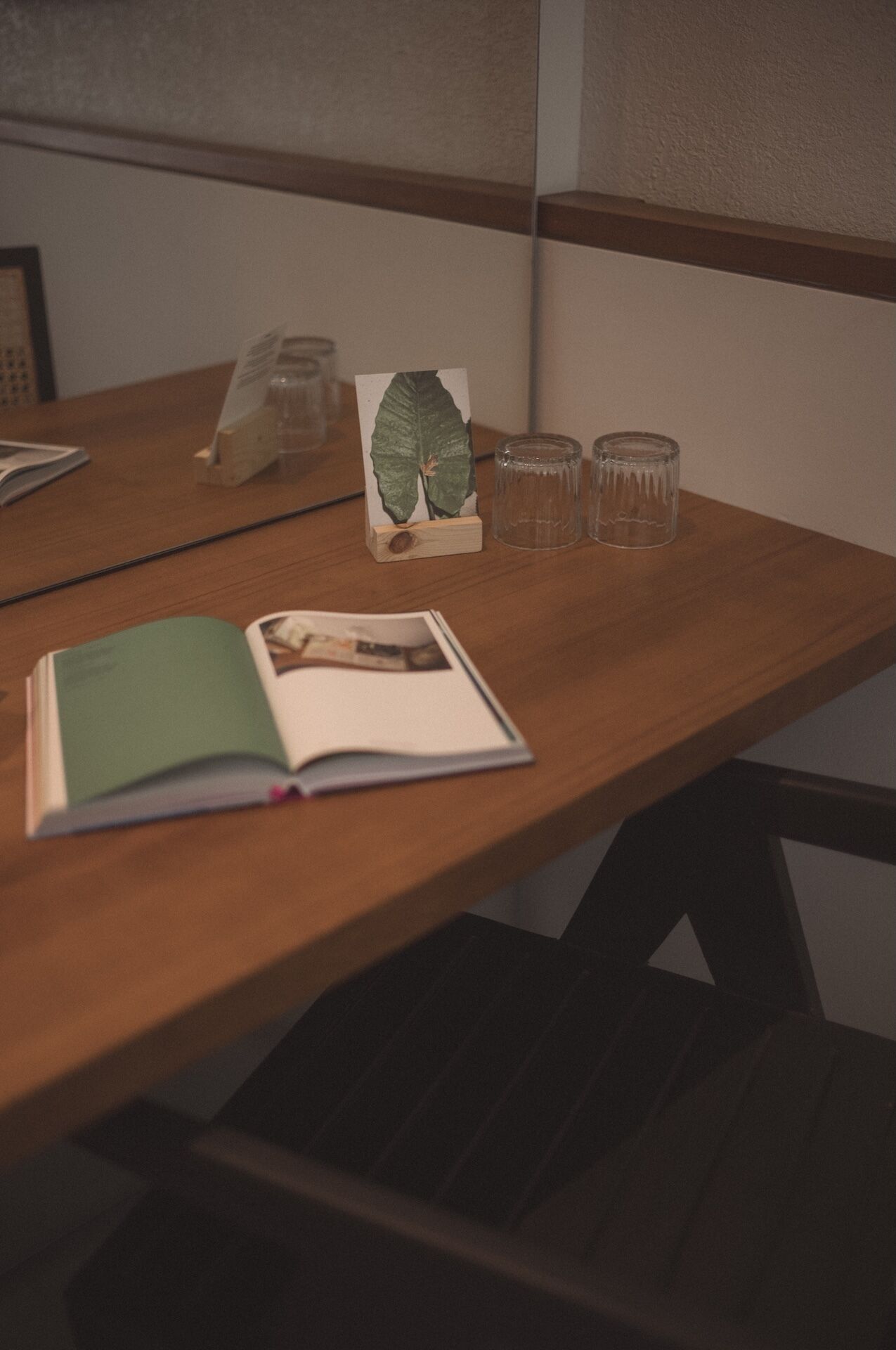 A wooden table with a book, a card, and two glasses.