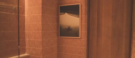 A bathroom with a toilet, a glass shower enclosure, and a picture on the wall.