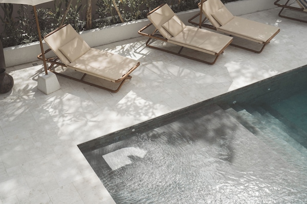 Una piscina al aire libre, sombrillas, sillones reclinables de piscina