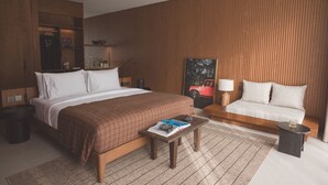 Een hotelkamer met een groot bed, een bank, een klein tafeltje en een houten accentmuur.