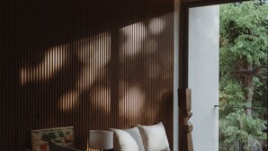 Een moderne slaapkamer met een bed, nachtkastje, lamp en uitzicht op groen.