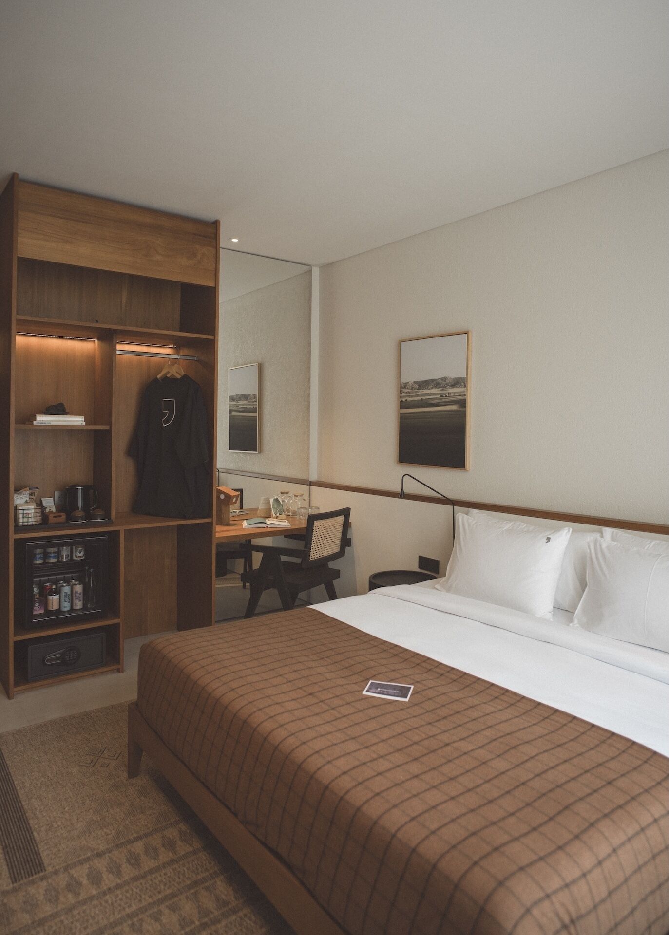 Une chambre d’hôtel avec un lit, un bureau, une armoire et un miroir.