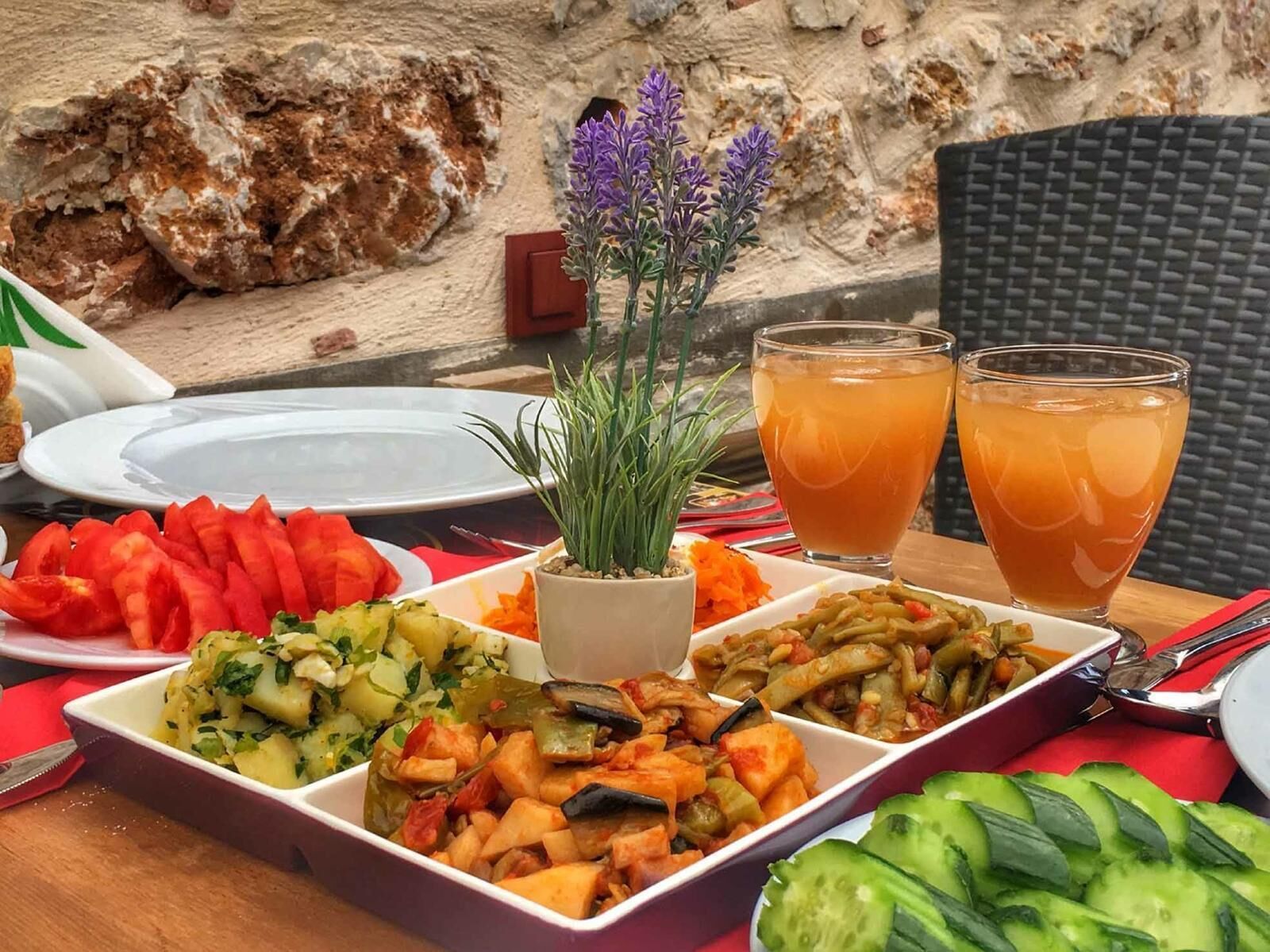 Una mesa con varios platos, una planta en maceta y dos vasos de una bebida.